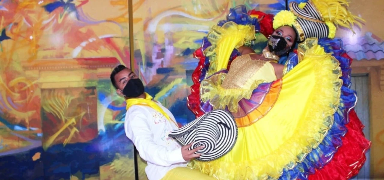 Pareja de bailarines con trajes coloridos y sombrero, fondo art&iacute;stico.