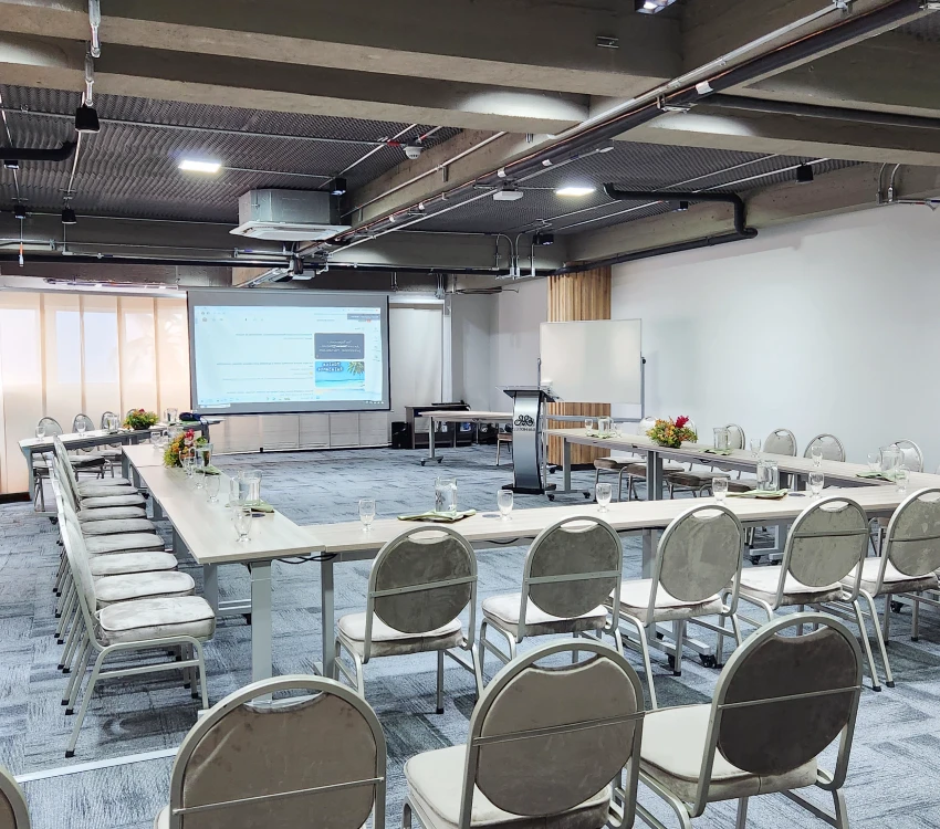Sala de conferencias con asientos y una pantalla de proyecci&oacute;n.