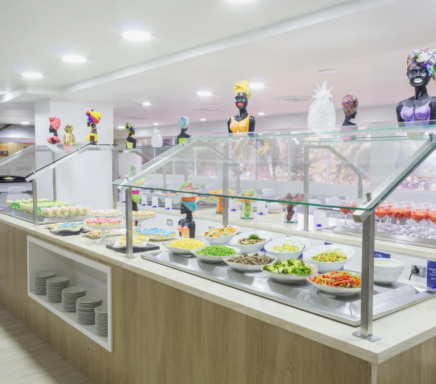 Buffet con variedad de ensaladas en exhibici&oacute;n bajo vitrinas de vidrio.