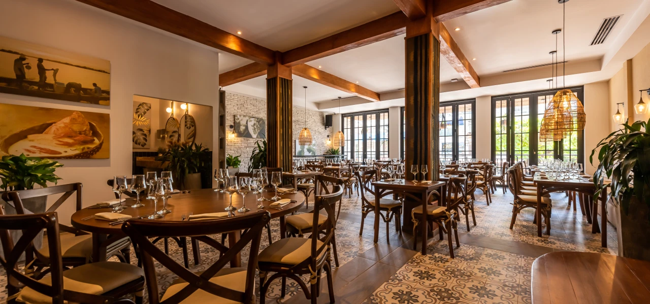 Restaurante elegante con mesas de madera, plantas y l&aacute;mparas colgantes.