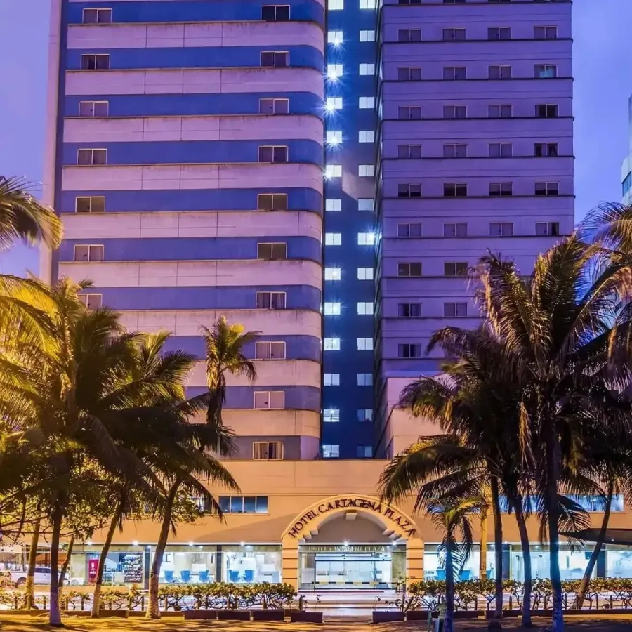 Edificio alto y palmeras iluminadas en la noche.