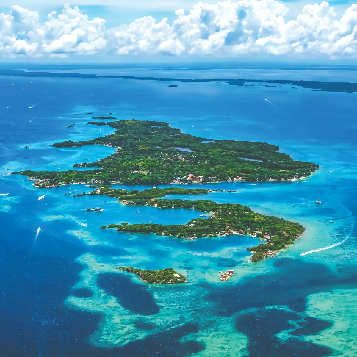 Isla tropical rodeada de mar azul y cielo con nubes blancas.