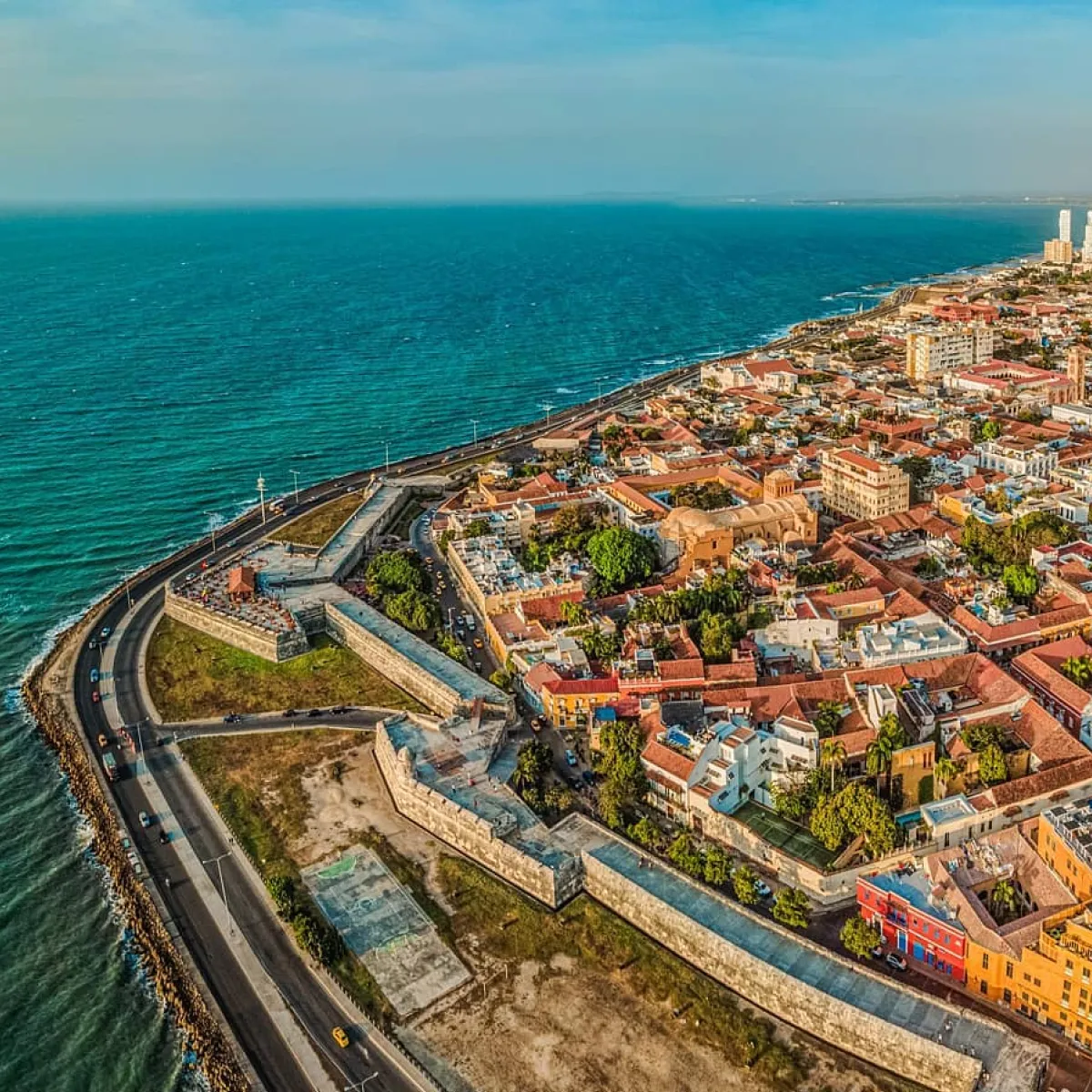 Vista aérea de una ciudad amurallada junto al mar con un camino costero.