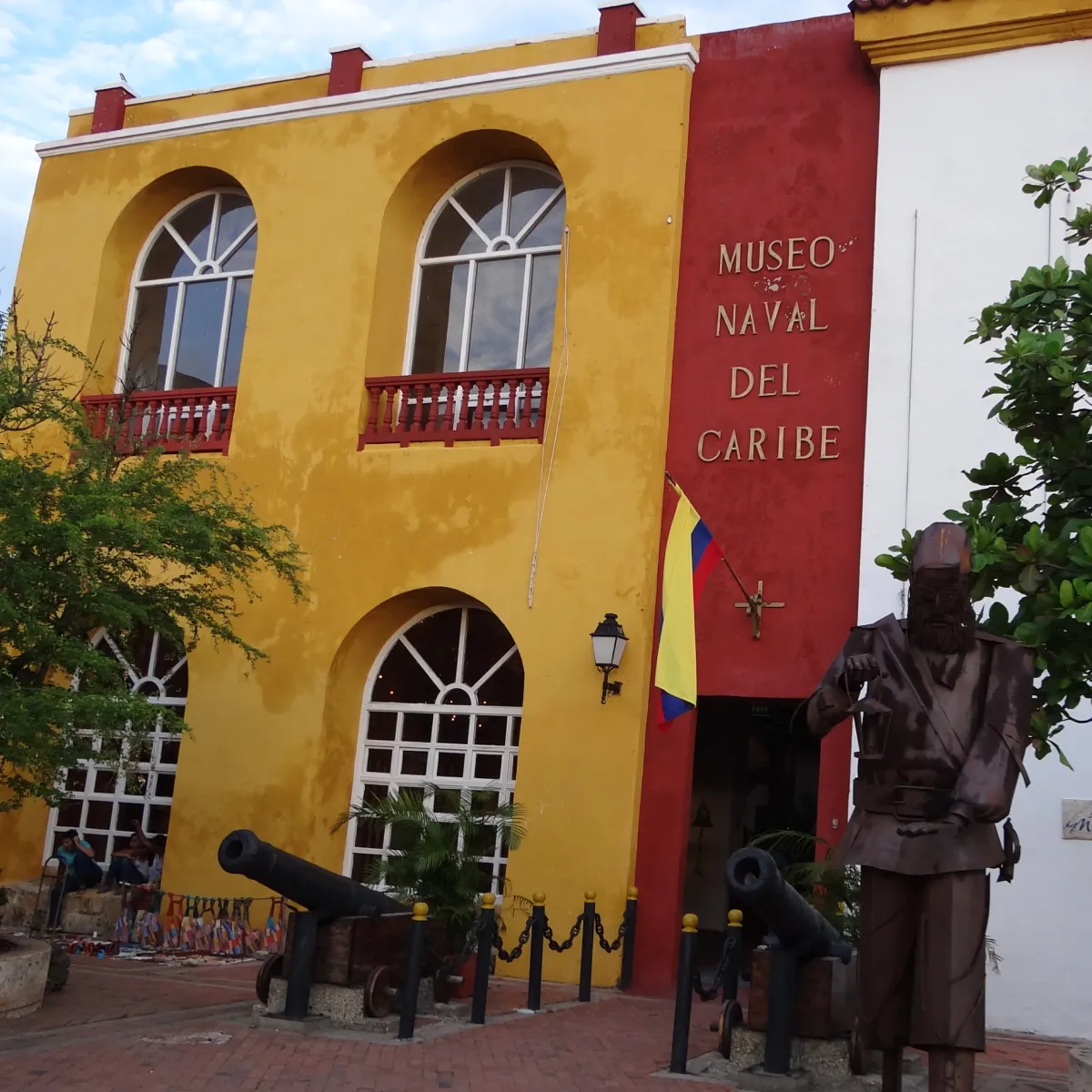 Fachada del Museo Naval del Caribe con estatua y cañones frente al edificio.