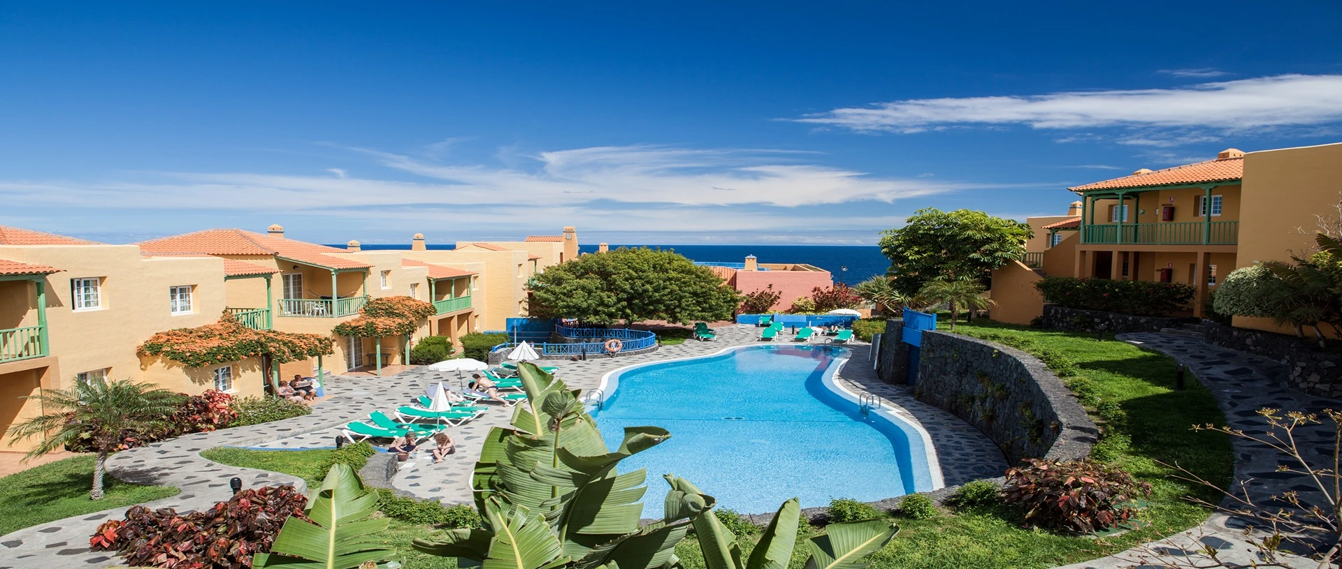 Complejo de apartamentos con piscina y jardines, vista al mar.
