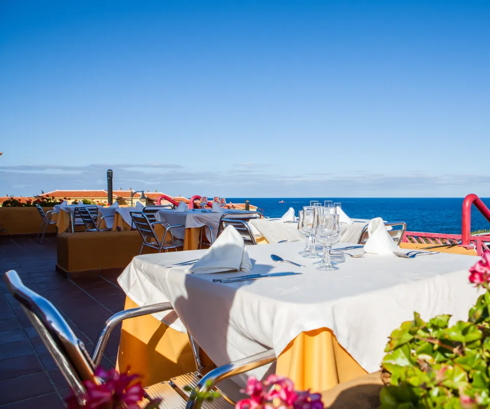 Mesa al aire libre con vista al mar en un d&iacute;a soleado.