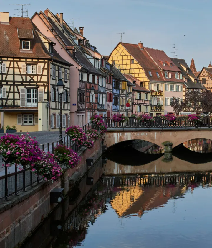 Maisons color&eacute;es &agrave; colombages le long d'un canal avec un pont fleuri.