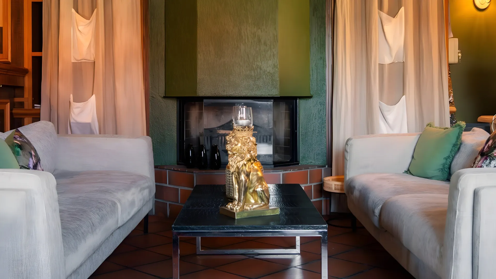 Deux canap&eacute;s autour d'une table avec une sculpture dor&eacute;e devant une chemin&eacute;e.