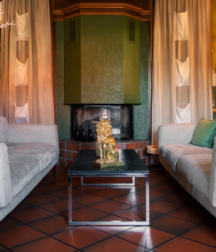 Salon cosy avec chemin&eacute;e verte, deux canap&eacute;s et table basse noire.