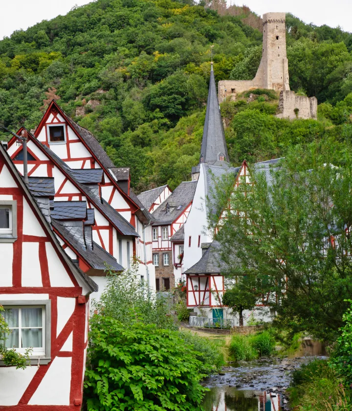 Maisons &agrave; colombages et ruine de ch&acirc;teau dans une vall&eacute;e verdoyante.