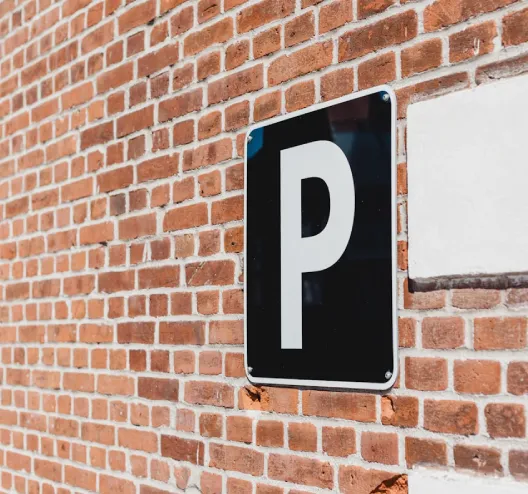 Panneau de parking sur un mur de briques rouges.