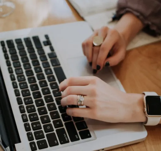 Mains tapant sur un clavier d'ordinateur portable, une main portant une montre.