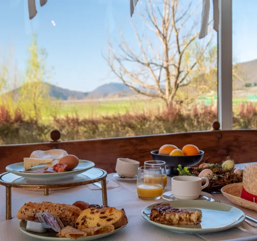 Petit-d&eacute;jeuner sur table ext&eacute;rieure avec vue sur la campagne ensoleill&eacute;e.
