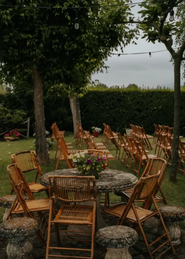 Ceremonia al aire libre con sillas de madera y arco floral en jard&iacute;n verde