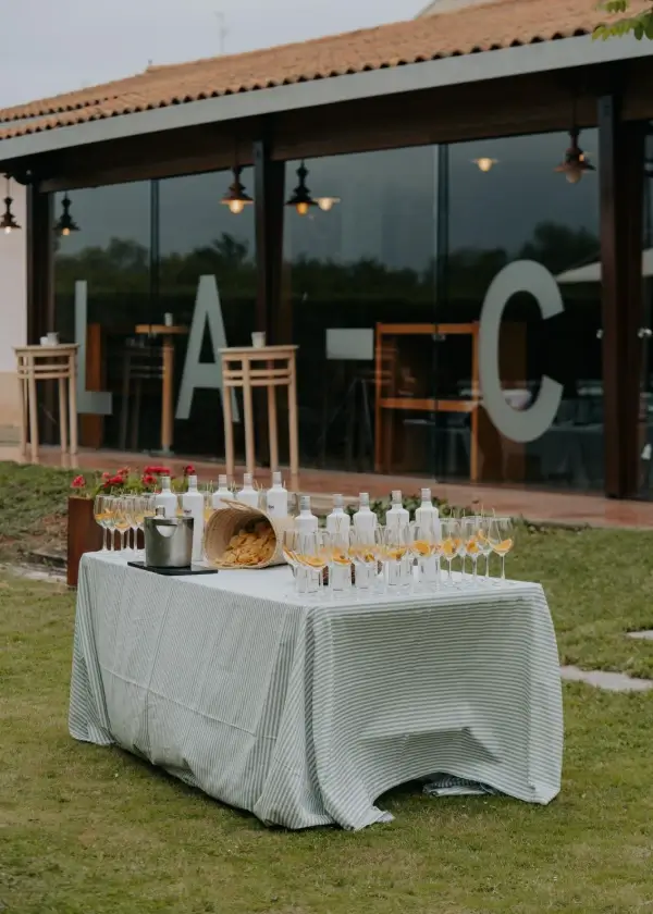 Mesa de bebidas en jard&iacute;n con &ldquo;A&rdquo; y &ldquo;C&rdquo; grandes frente a un patio cubierto