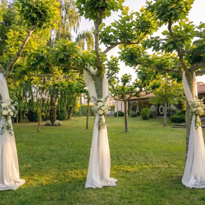 Arco de boda con telas blancas y arreglos florales en un jard&iacute;n verde