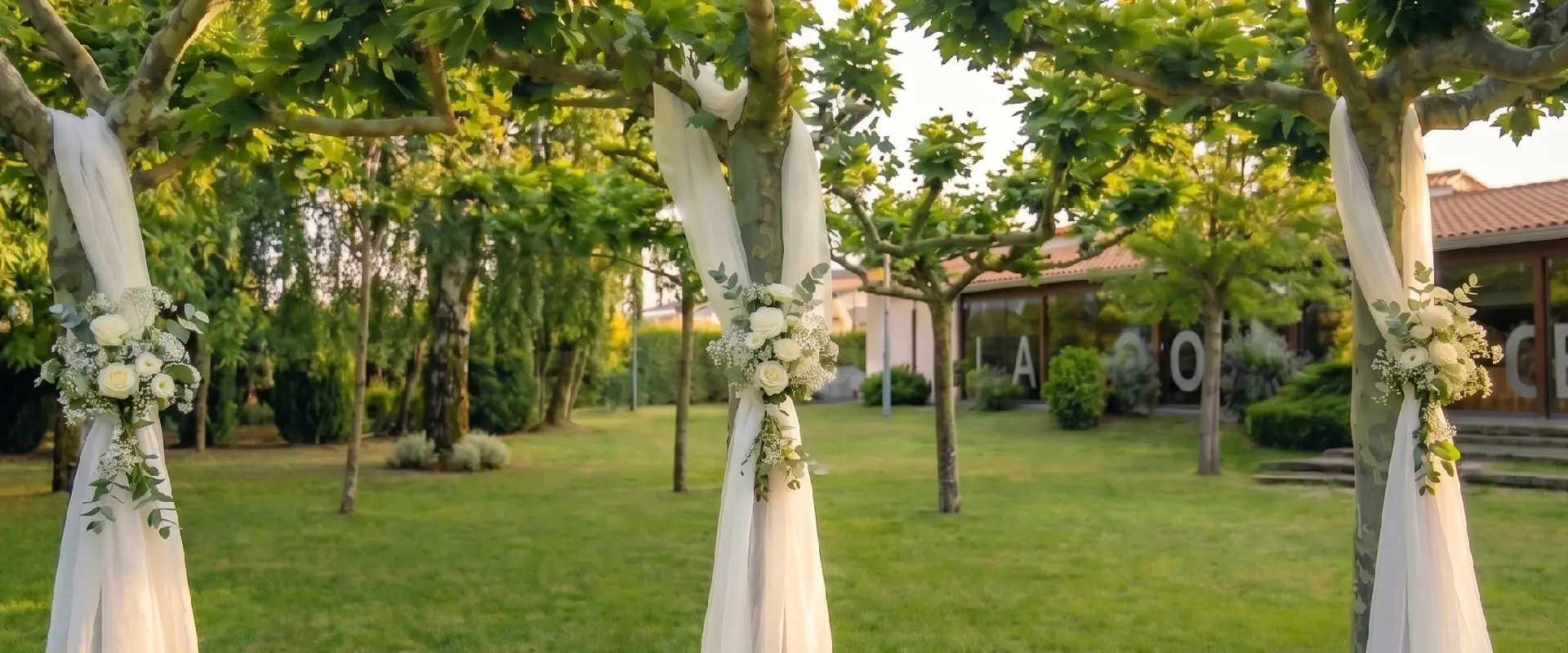 Arcos con telas blancas y flores en un jard&iacute;n, camino hacia el altar.