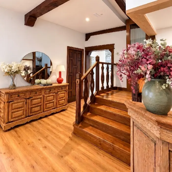 Interior de sala r&uacute;stica con escalera de madera y floreros de flores rosas y blancas