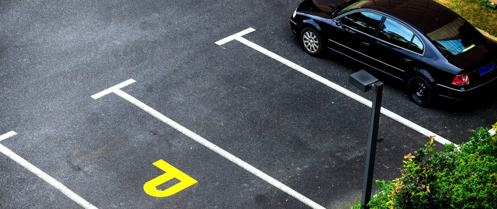 Coche negro estacionado junto a flechas de carril en una carretera asfaltada