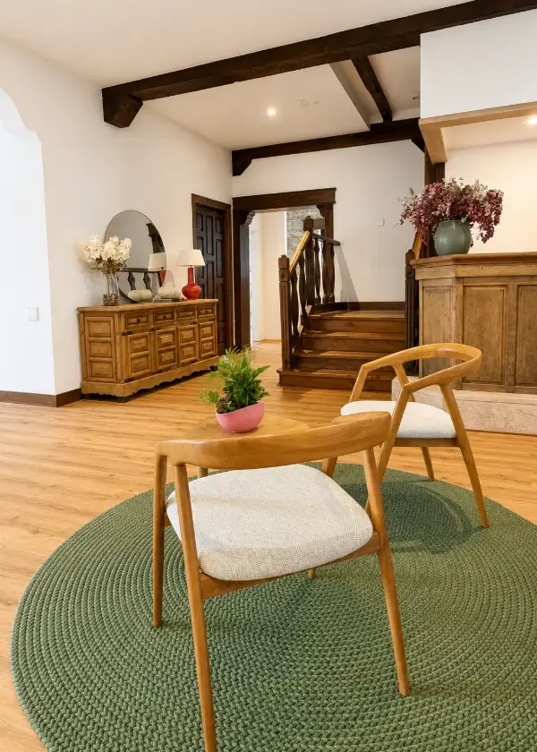 Sala interior con sill&oacute;n de madera, alfombra verde y mesa de recepci&oacute;n.