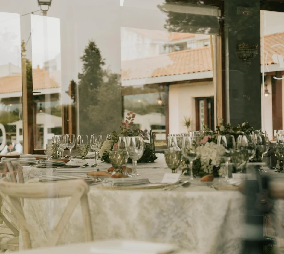 Mesa servida con copas de vino y decoraci&oacute;n floral en terraza.