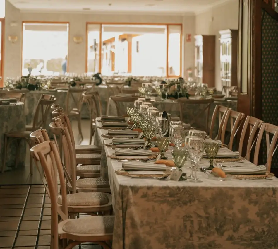 Mesa decorada con cubiertos y copas en un sal&oacute;n para eventos