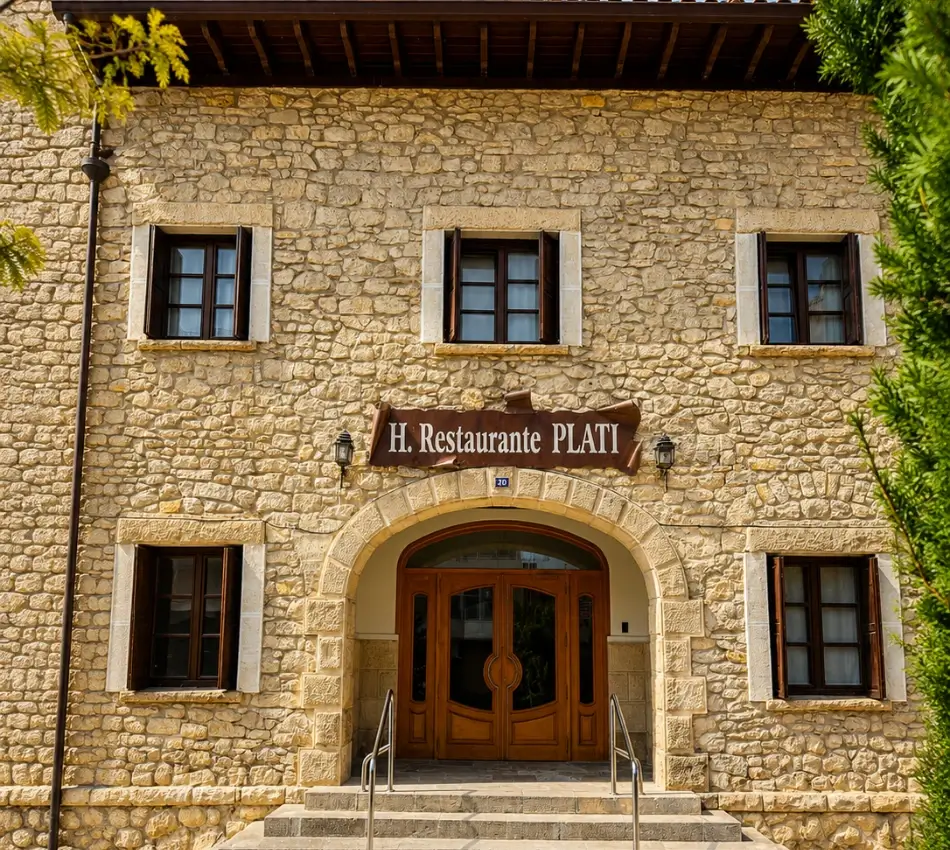 Fachada de piedra con letrero &ldquo;H. Restaurante PLATI&rdquo; y puerta de entrada.