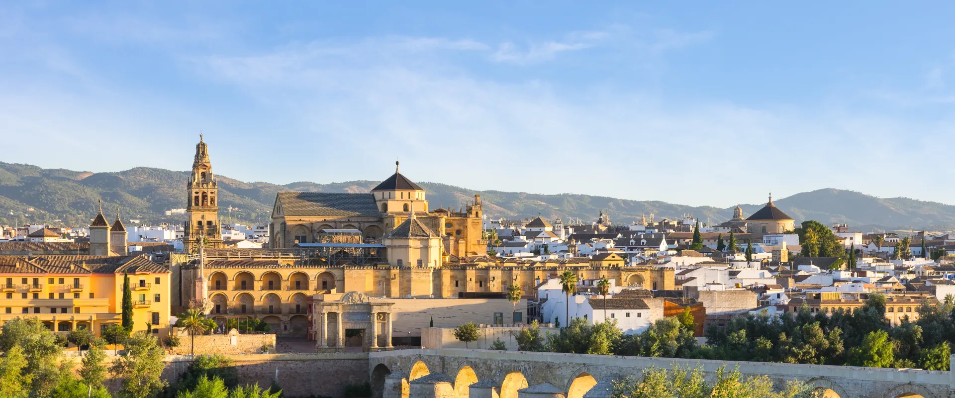 Vista panor&aacute;mica de ciudad hist&oacute;rica con monta&ntilde;as al fondo y cielo despejado.
