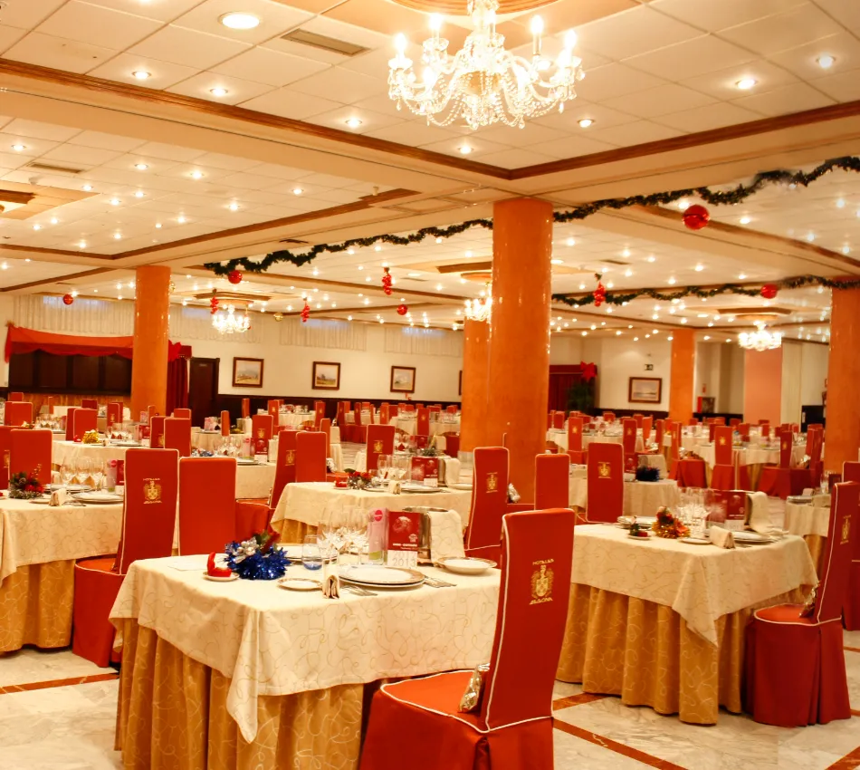 Restaurante elegante decorado para una celebraci&oacute;n con mesas dispuestas y candelabros brillantes.