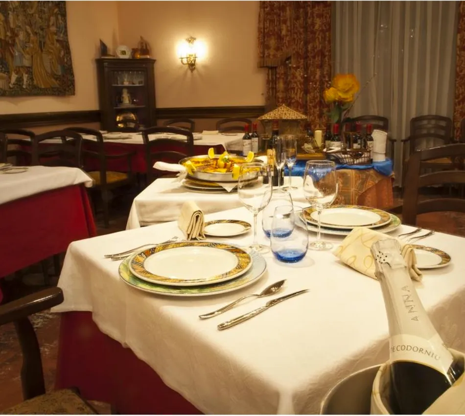 Mesa elegante con platos, copas y cubiertos en un restaurante acogedor, listo para cenar.