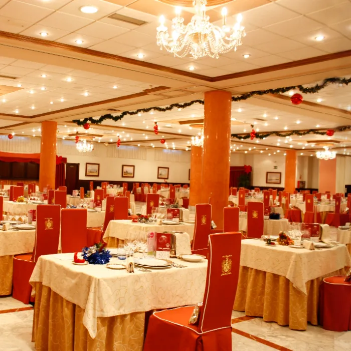 Comedor elegante con mesas preparadas y decoraciones navide&ntilde;as.