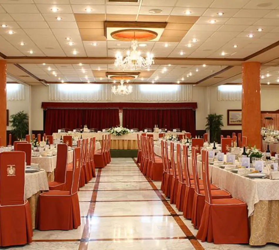 Sal&oacute;n de banquetes elegantemente decorado para un evento con mesas dispuestas en filas.
