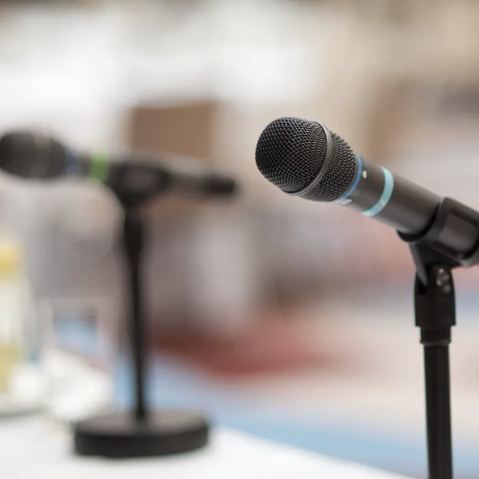 Micr&oacute;fonos sobre soportes en una sala, preparados para una conferencia o evento.