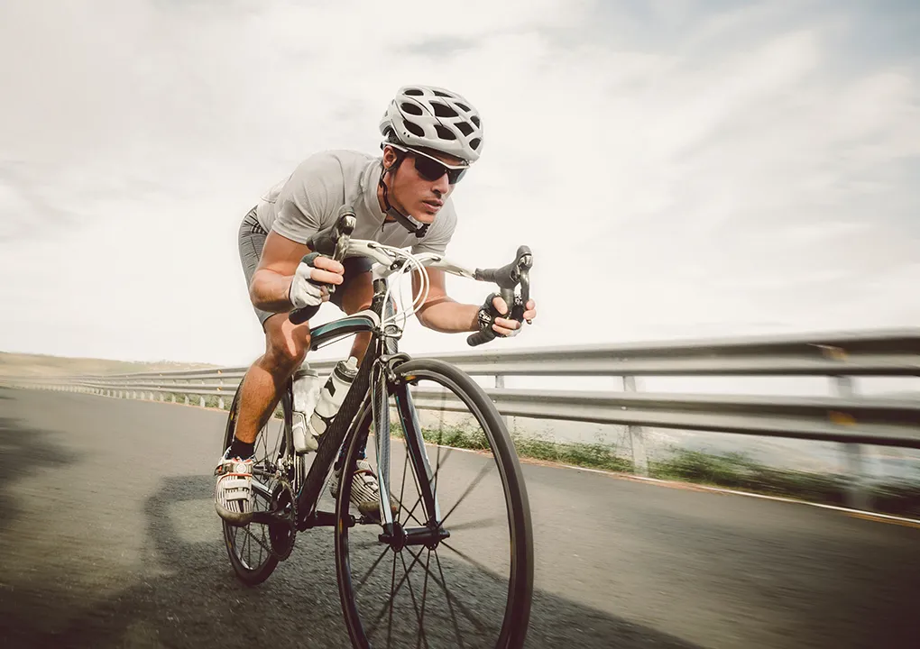 Ciclista en carretera con traje y casco, en postura aerodin&aacute;mica.