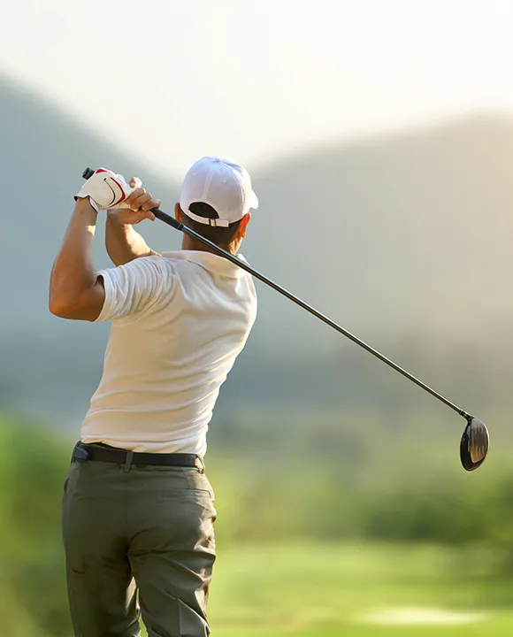 Persona jugando golf en un campo con monta&ntilde;as al fondo.