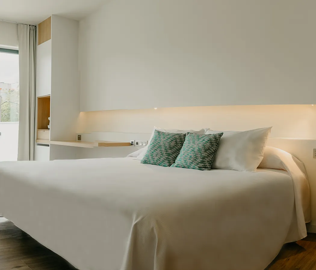 Habitaci&oacute;n de hotel moderna con cama grande y cojines decorativos.