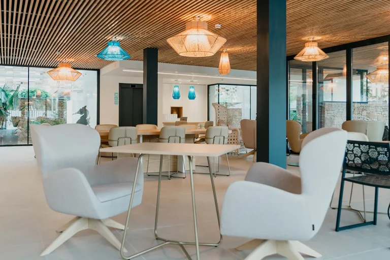 Sala moderna con sillas grises y l&aacute;mparas colgantes coloridas.