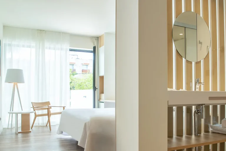 Habitaci&oacute;n minimalista con cama, l&aacute;mpara y lavabo moderno a la vista.