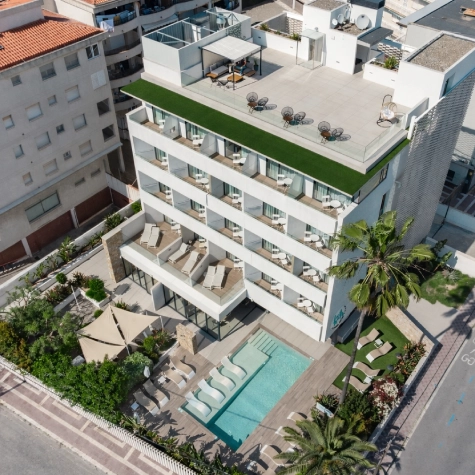 Vista a&eacute;rea de un edificio moderno con piscina y terraza en la azotea.