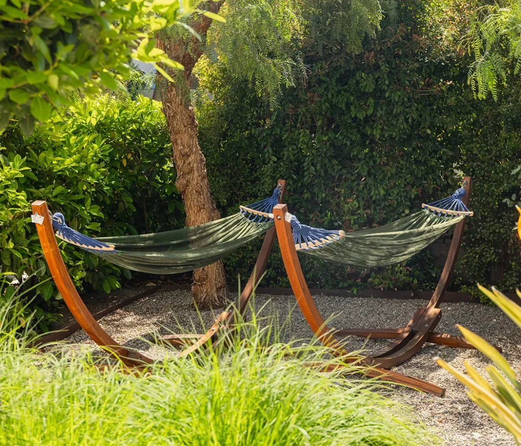 Hamacas verdes en un jard&iacute;n rodeado de vegetaci&oacute;n.