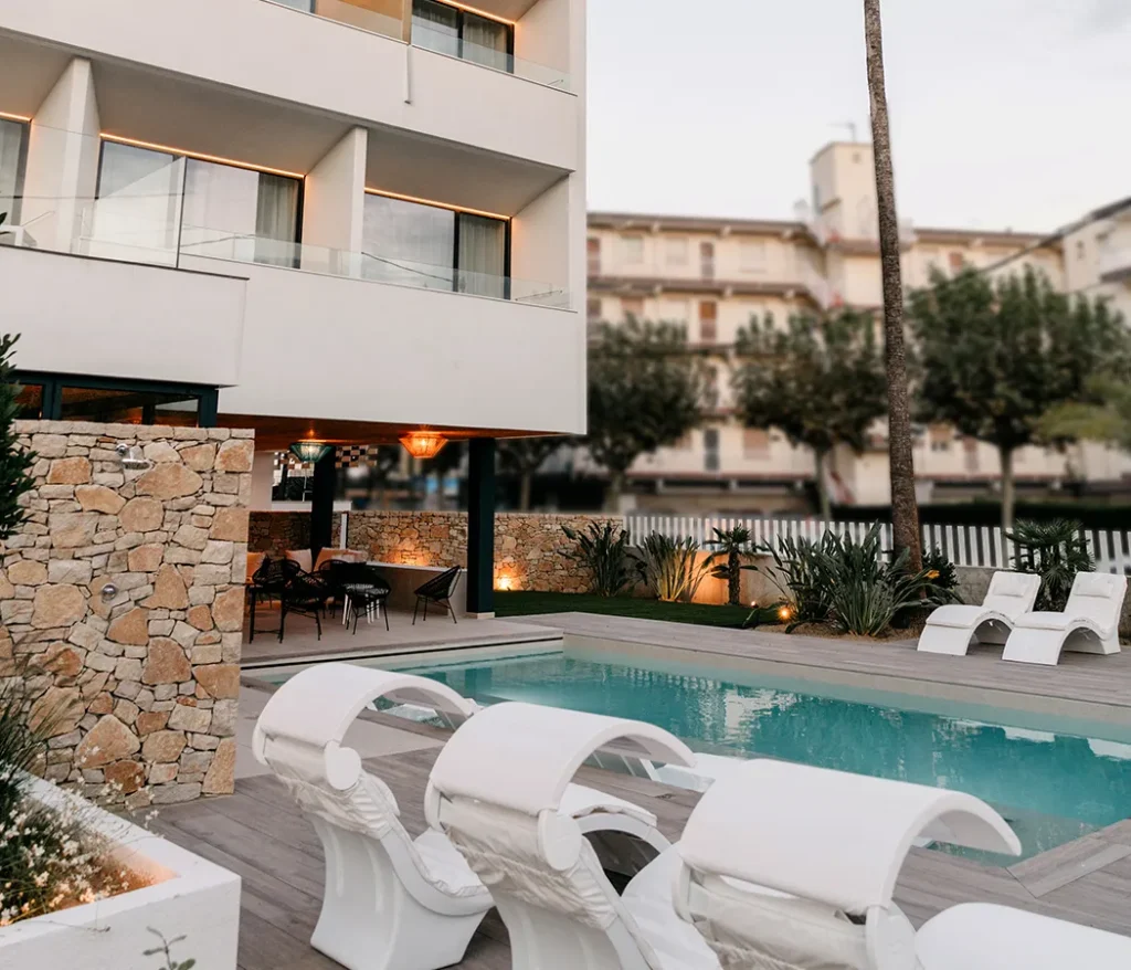 Piscina moderna con tumbonas y edificio de fondo.