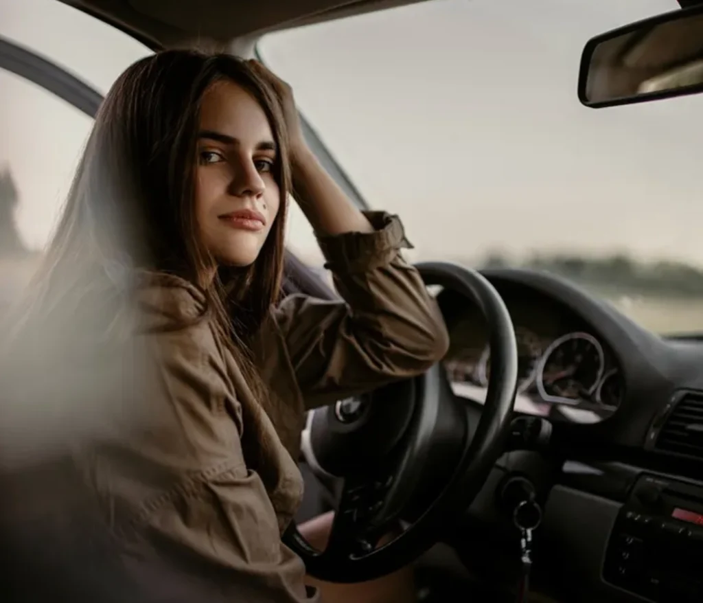 Mujer en un coche, mirando hacia atr&aacute;s con una leve sonrisa.
