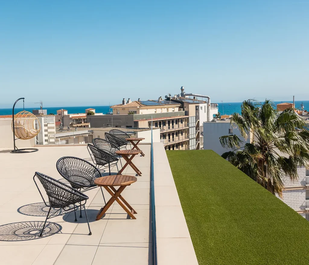 Terraza con sillas, mesas y vistas al mar en una ciudad junto a la costa.