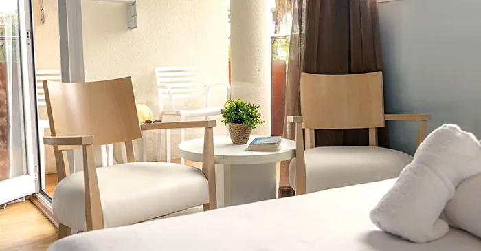 Dos sillas y una mesa en una habitaci&oacute;n, con toallas en primer plano.