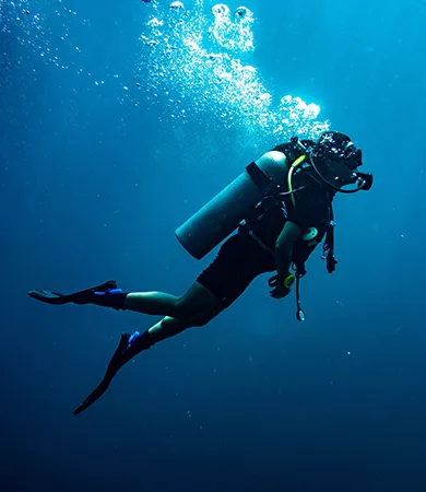 Buceador con equipo completo bajo el agua rodeado de burbujas.
