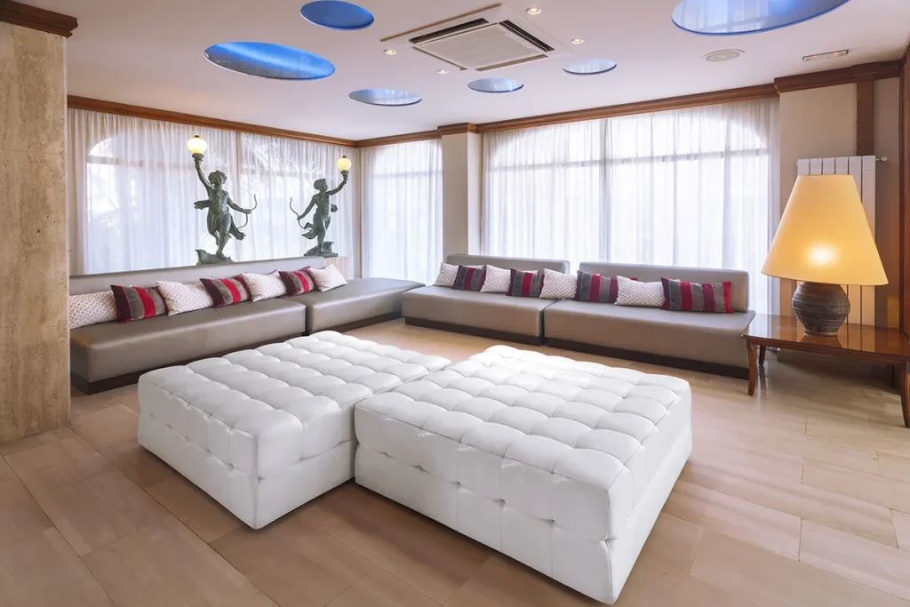 Sala de estar moderna con sof&aacute;s grises y pufs blancos.