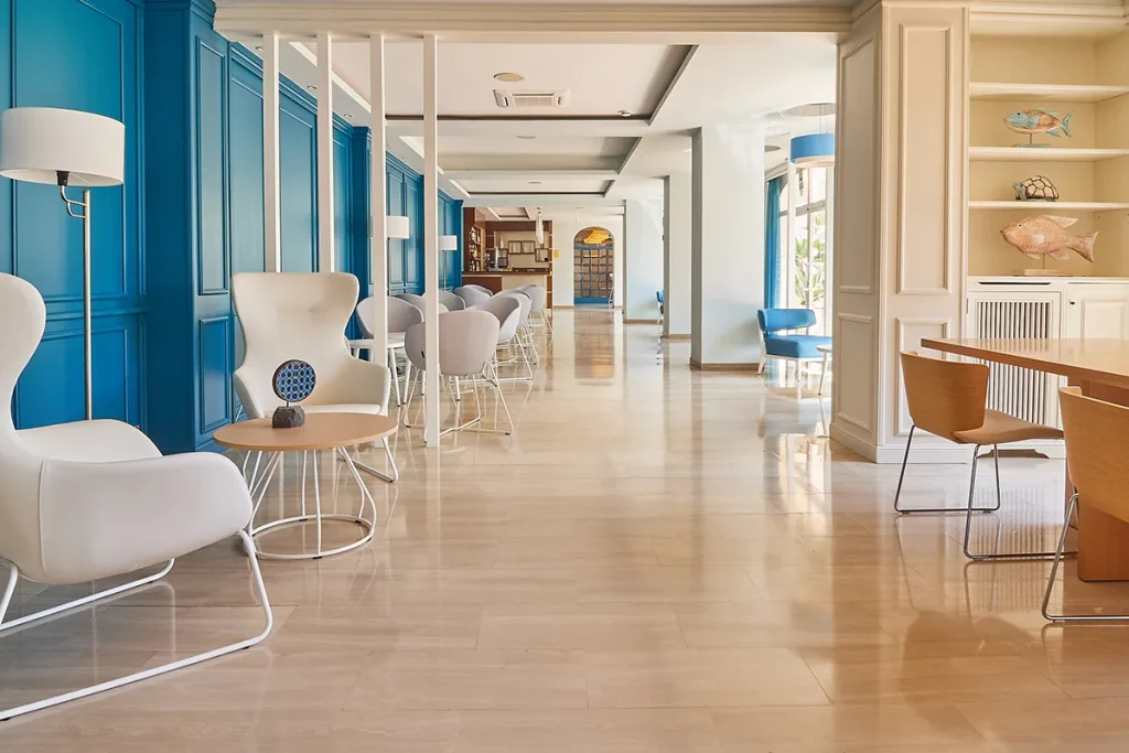 Sala de estar moderna con sillas blancas, mesas de madera y pared azul.