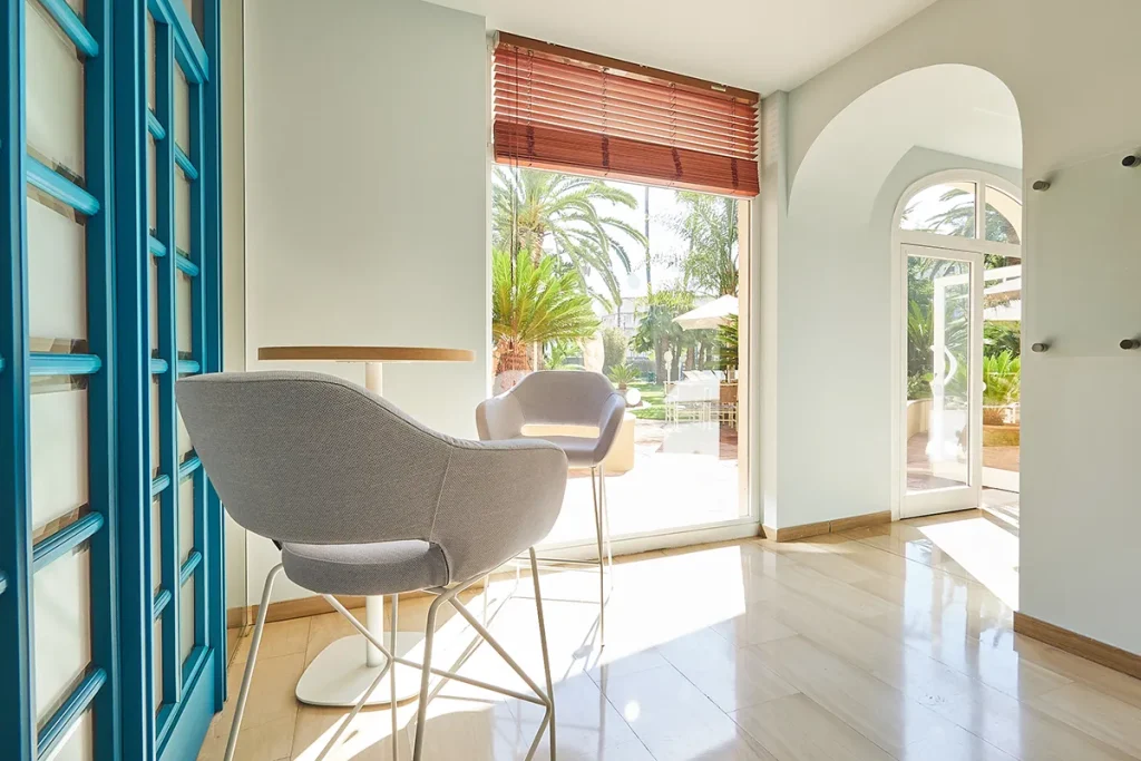 Sillas modernas junto a una mesa en una sala luminosa con vista al jard&iacute;n.