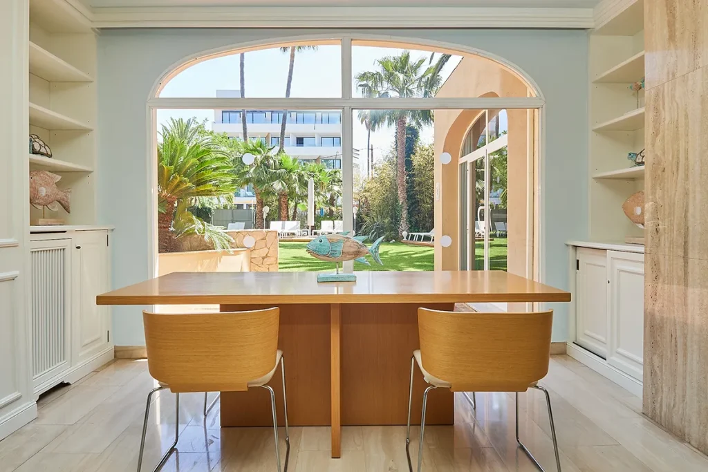 Mesa con sillas en sala de estar con ventana y vista al jard&iacute;n.