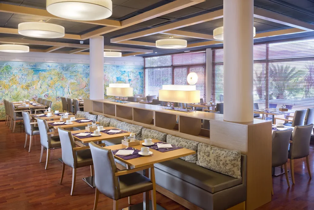 Restaurante moderno con mesas de madera, sillas grises y decorado art&iacute;stico.